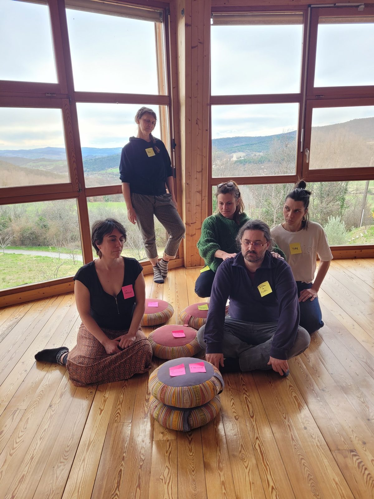 Cinq participants réunis dans la yourte, devant la baie vitrée ouverte sur la vallée