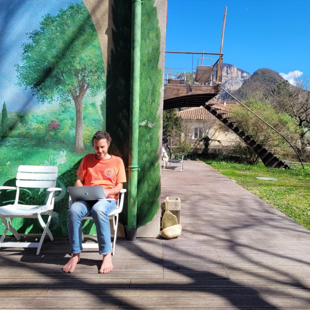 Un participant à l'ordinateur sur la terrasse, au soleil