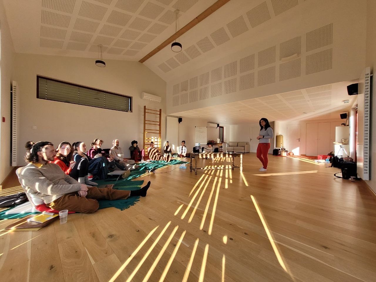 La salle d'atelier au soleil rasant, le groupe assis au sol